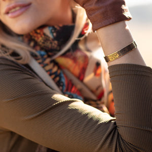 Women shooting with gold engraved bracelet with tweed, leather and country silk scarf fashion